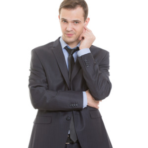 body language. man in business suit isolated on white background. scratching, rubbing the ear. gesture of distrust speaker